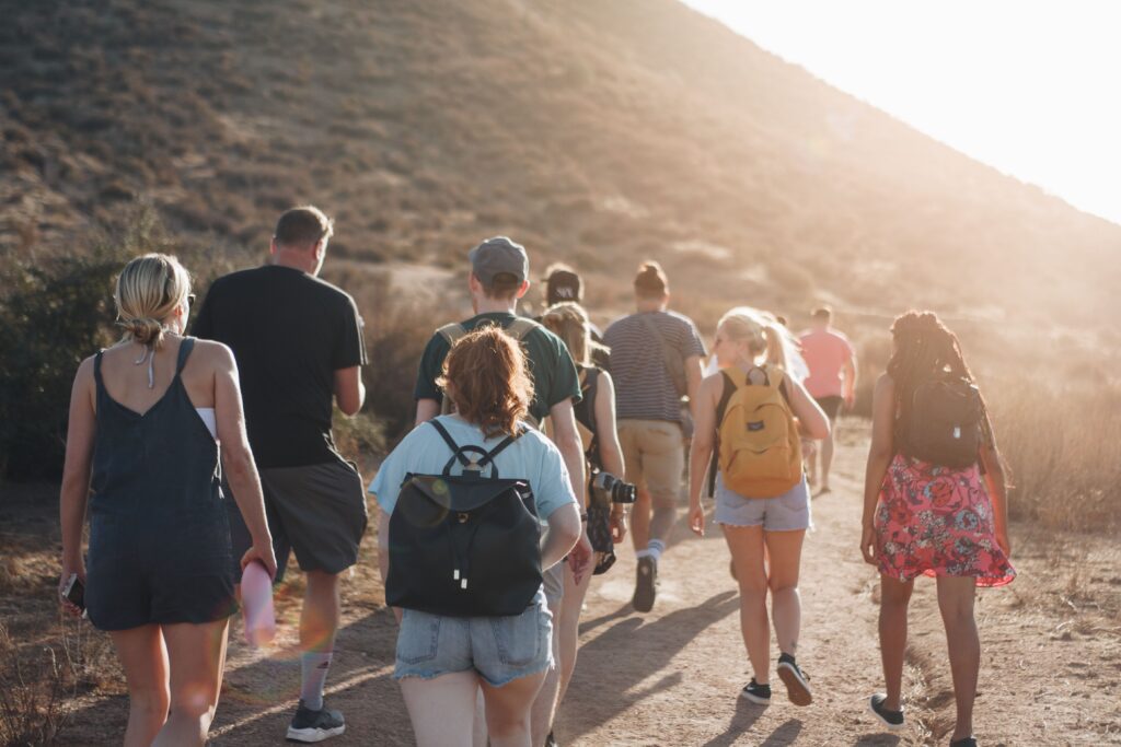 Large group walking with backpacks on on a track near a hill