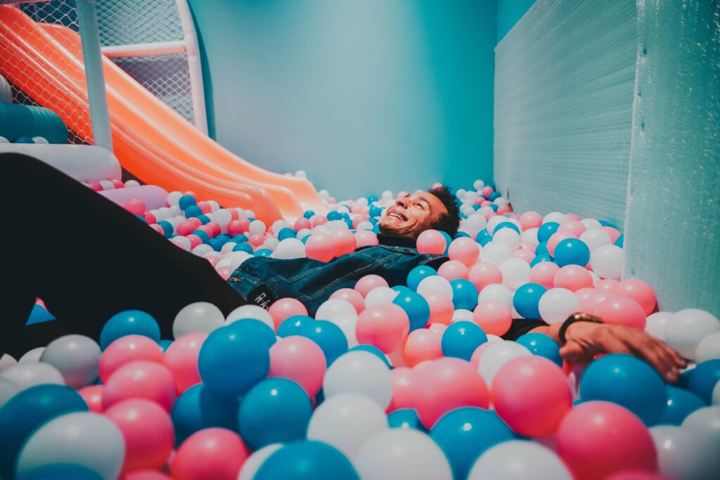 A Man Lying on Balls in a Ball Pit showcasing a fun way to introduce activities at events