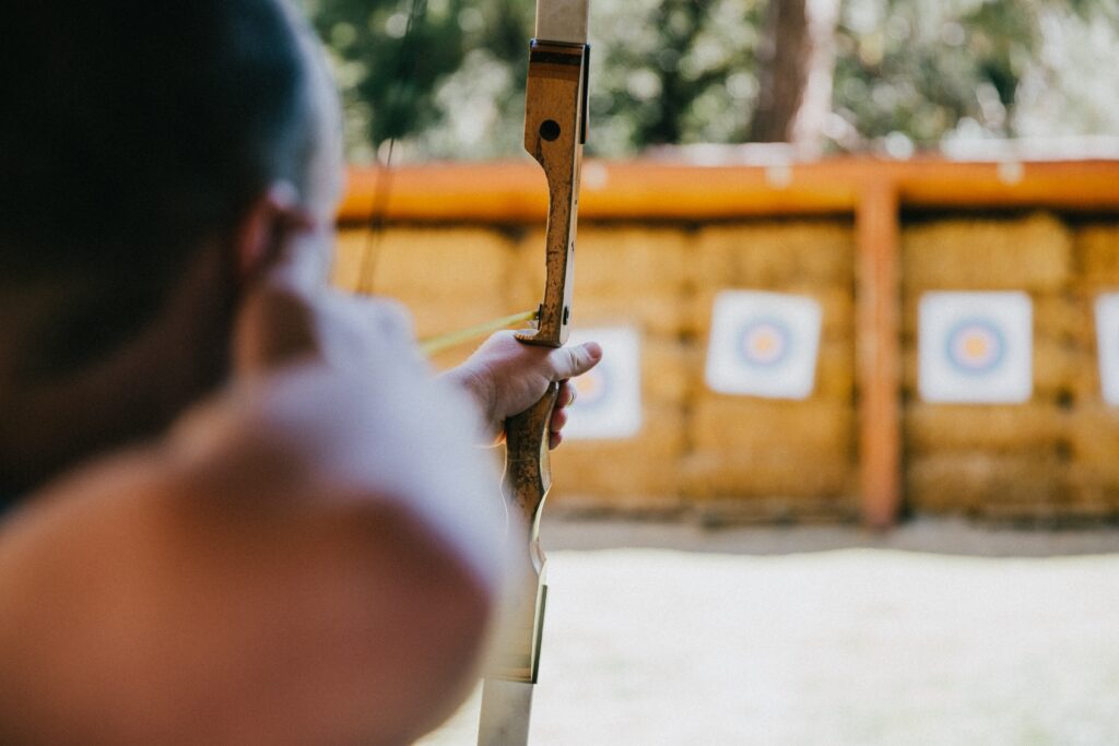 Blurred shot from back of someones head as they're pulling an arrow towards an archery board