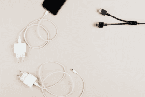 Phone chargers and an iphone on a blank cream table