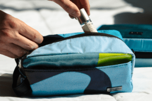 Man putting toiletries inside a toiletry bag blue in colour with swirls and a top zip 