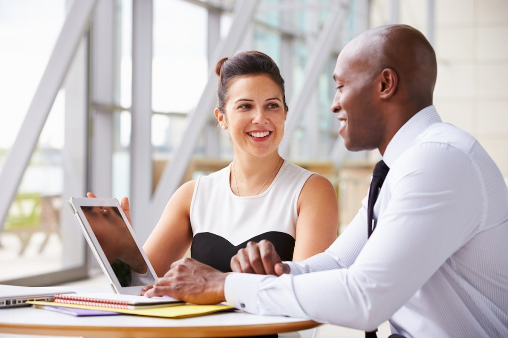 Two event organizers sit side by side at a table discussing the 2023 event industry forecast and what it means for their budgeting and contract negotiations.