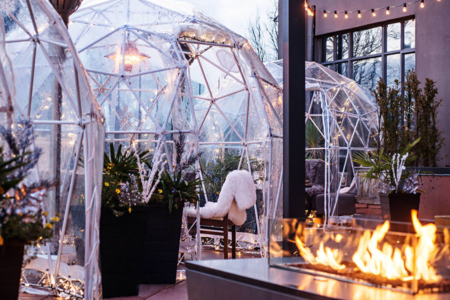 Igloo-like domes constructed from a metallic frame and clear plastic covering provide shelter to outdoor diners ready to enjoy the new al fresco event trend.