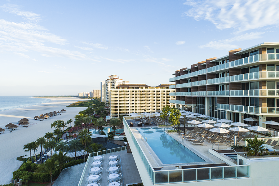 An outdoor view of the JW Marriott Marco Island showcases its beachside pool with chaise lounges and umbrellas, in keeping with the event trend towards greater emphasis on bleisure.