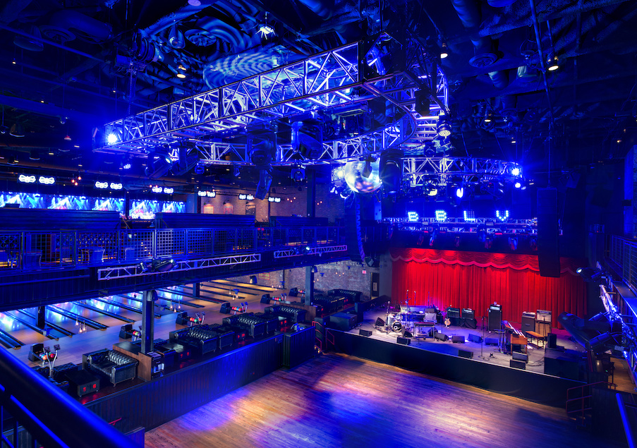 An overhead view of the live music stage and dance hall at the Brooklyn Bowl in Las Vegas, with bowling lanes visible on the left-hand side.