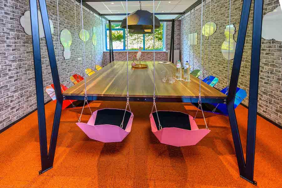A private meeting room with a board table surrounded by innovative "swing" chairs suspended from the ceiling.