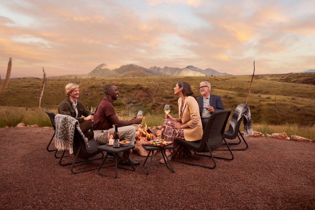 A meeting group enjoys an outdoor meal around a small bonfire in Arizona's Sonoran desert after a day of outdoor team-building activities.