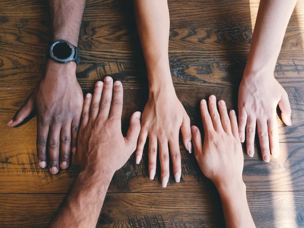 five human hands on brown surface photo