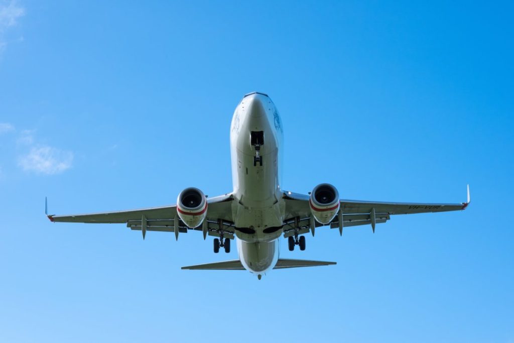 A large jetliner flying through a blue sky at Gold coast airport