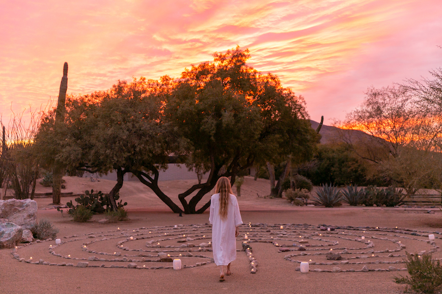 A woman stands under a desert sunset surrounded by a maze of candles and pebbles laid out on the sand at CIVANA resort — busting yet another meeting myth that business events don't always have to happen where they're Wi-Fi.