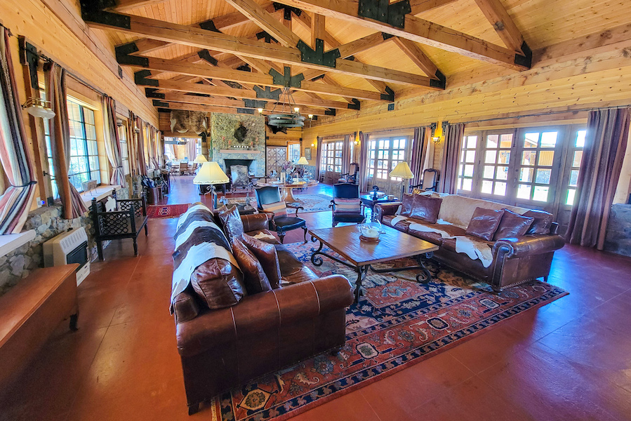 An interior view of Terra Farm + Manor, with leather couches and wooden beams along a cathedral ceiling overhead.