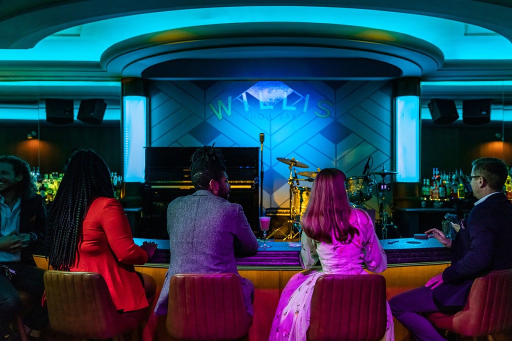 An interior shot of the Willis Show bar in Detroit. Guests are lined up at a 1940s-style bar facing a performance stage.