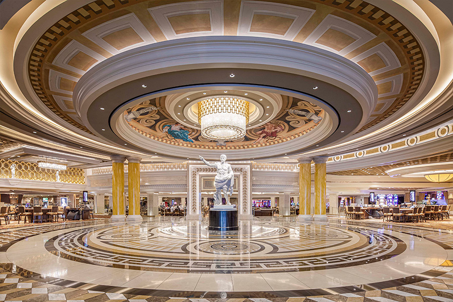 An interior shot of the lavish lobby of Caesars Palace complete with ornate tiling and a central statue of Caesar.