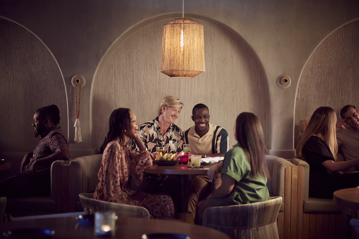 Four people sit around a table in a cozy restaurant enjoying an event's F&B experience.