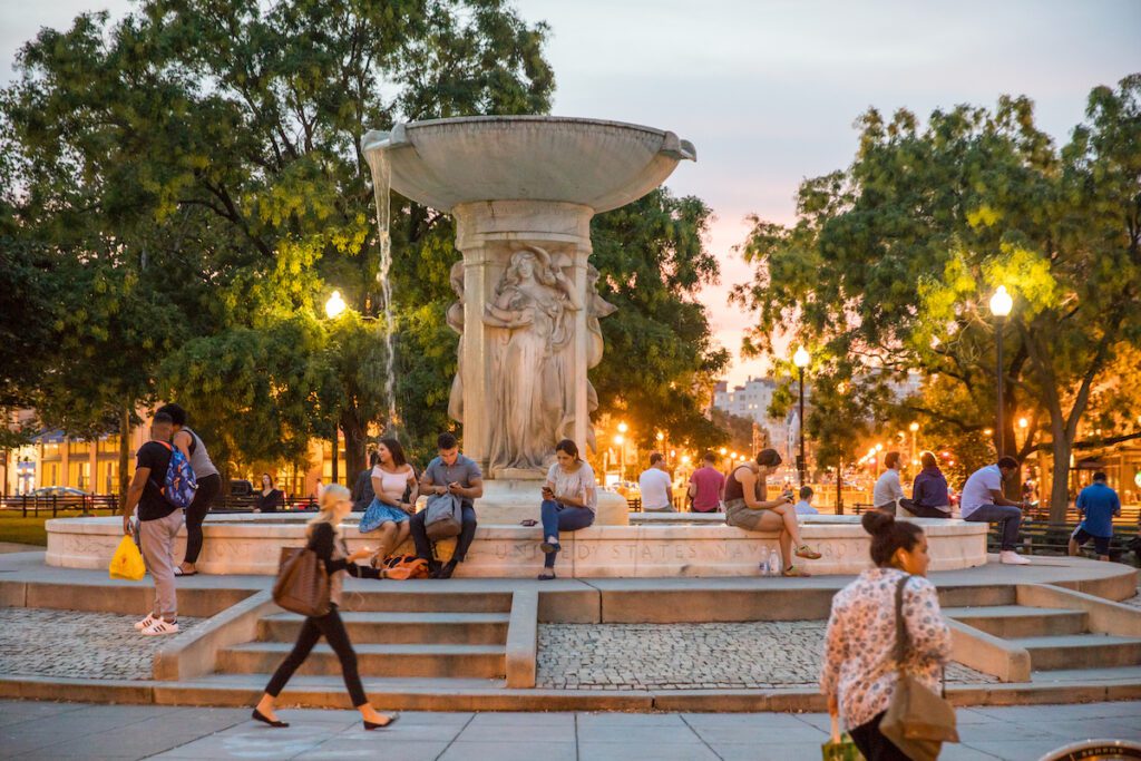An evening view of folks sitting and walking together around Dupont Circle in Washington DC, a top destination for these kinds of 