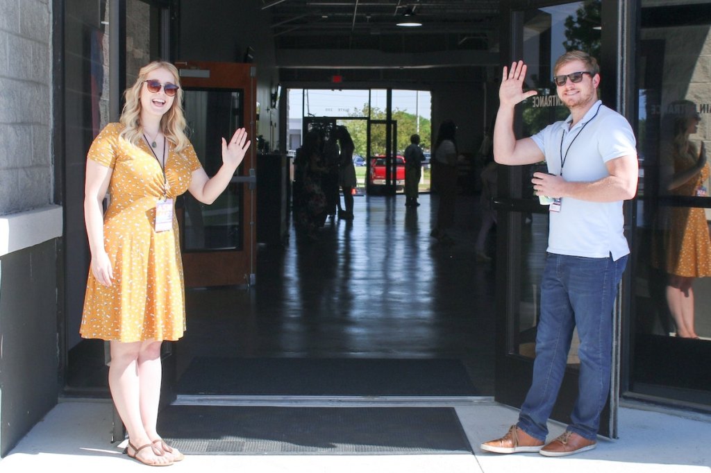 Two man and woman standing on doorway photo welcoming people as they come in