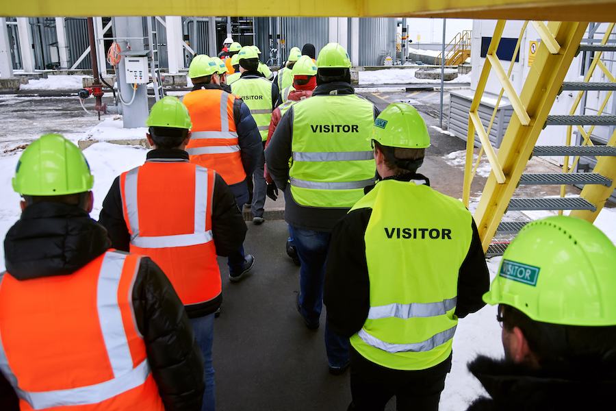 Attendees go on a factory tour in hard hats and reflector jackets as part of an event legacy project.
