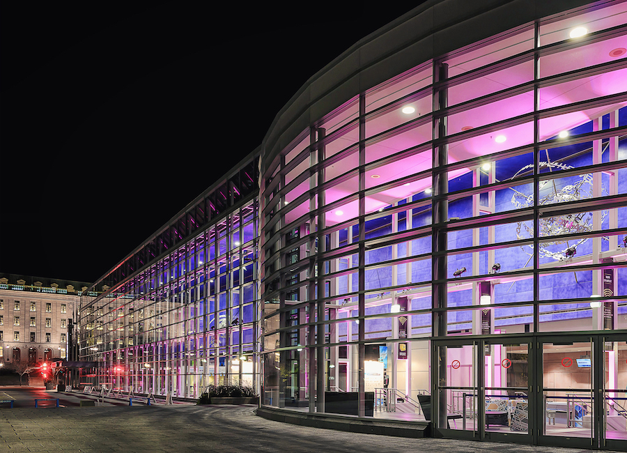 The Quebec City Convention Center at night, with purple lighting emanating from the large windows that form the exterior wall.
