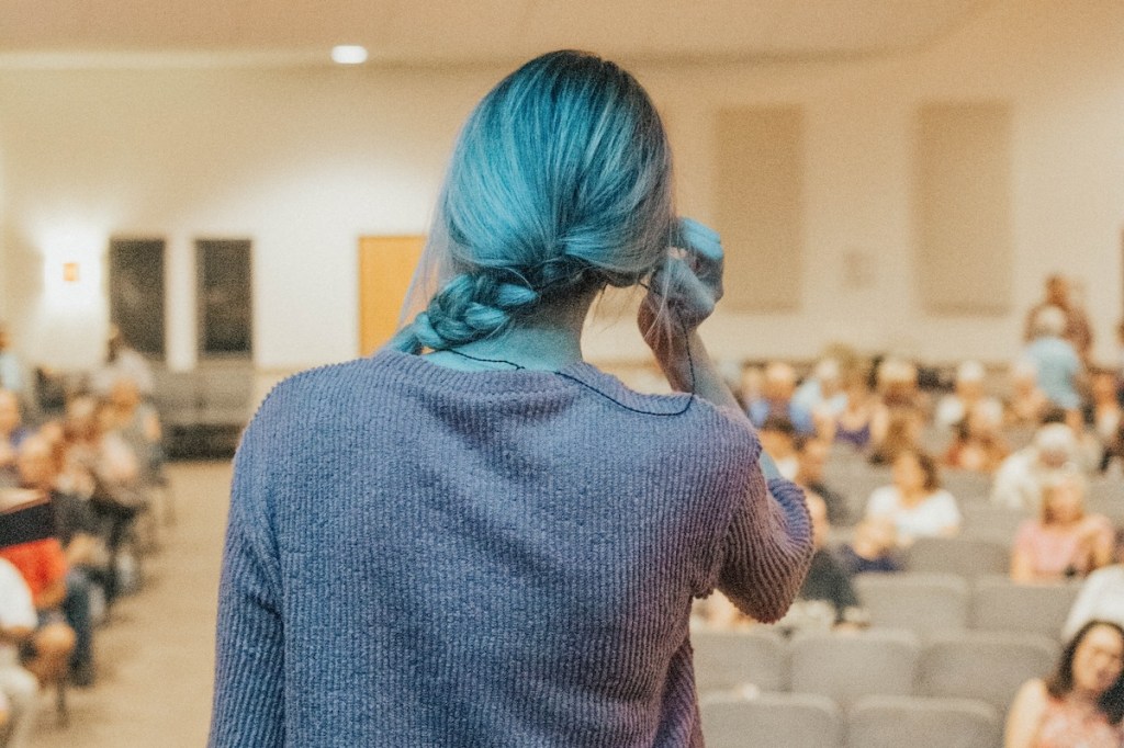 A woman speaker standing on stage in front of an audience.