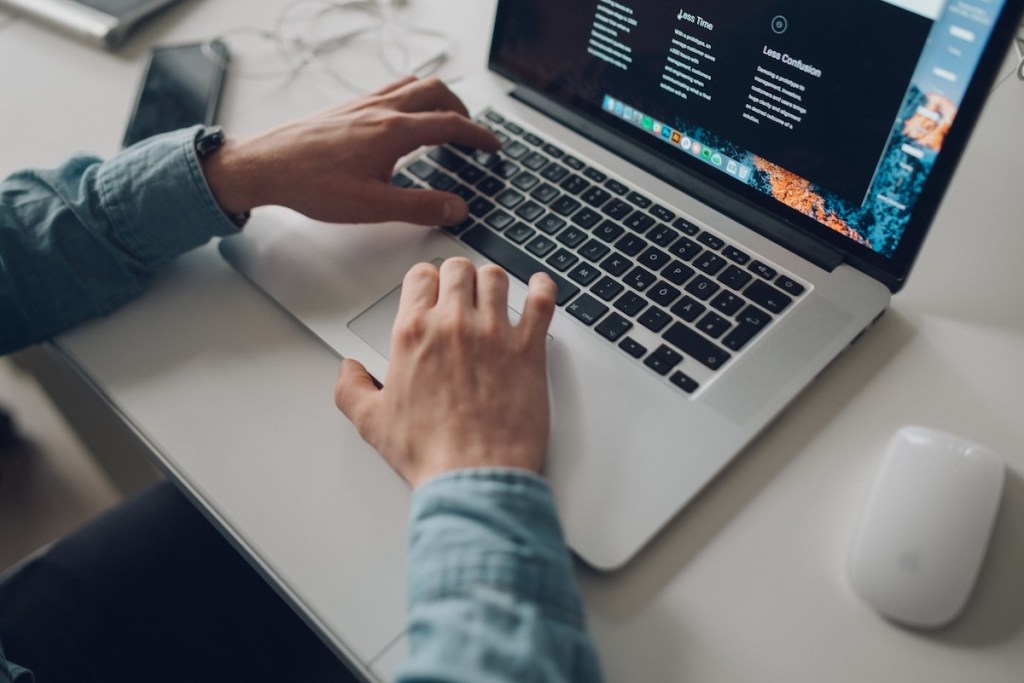 Person wearing long-sleeve top working on laptop