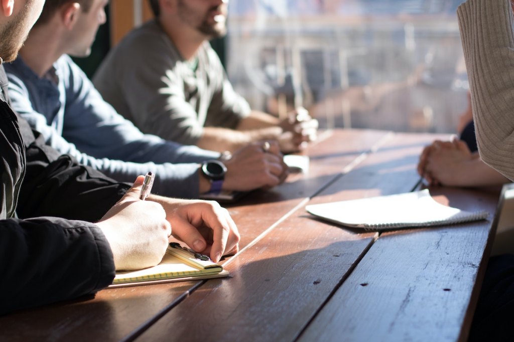 Group of event professionals sitting at negotiation table.