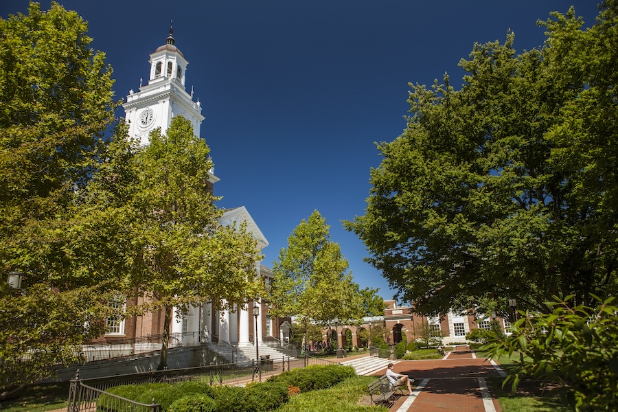 A view of the Johns Hopkins University campus, with large trees and a 19th-century building featuring red bricks, white columns, and a clock tower. JHU is one of the most prestigious research centers in the U.S., with a strong reputation for medical research in particular. This kind of innovation is part of the reason that Baltimore is emerging as a tech hub perfect for innovative events, meetings, and conferences.