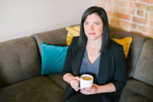 Business woman holding cup of coffee sitting on sofa in an office