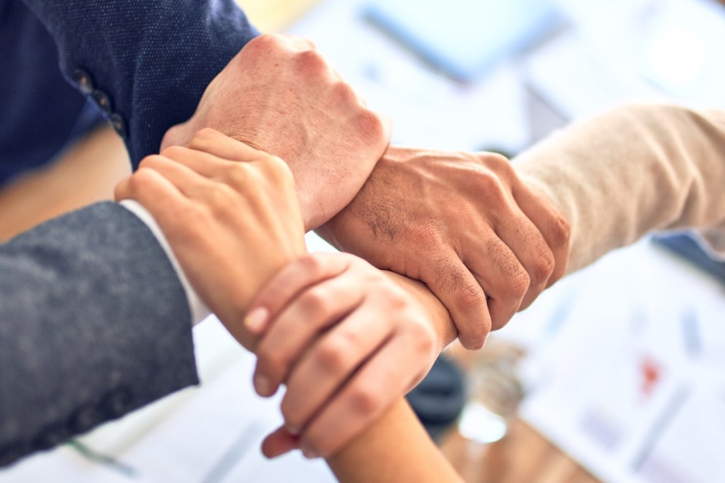 Group of business workers standing with hands together doing symbol at the office