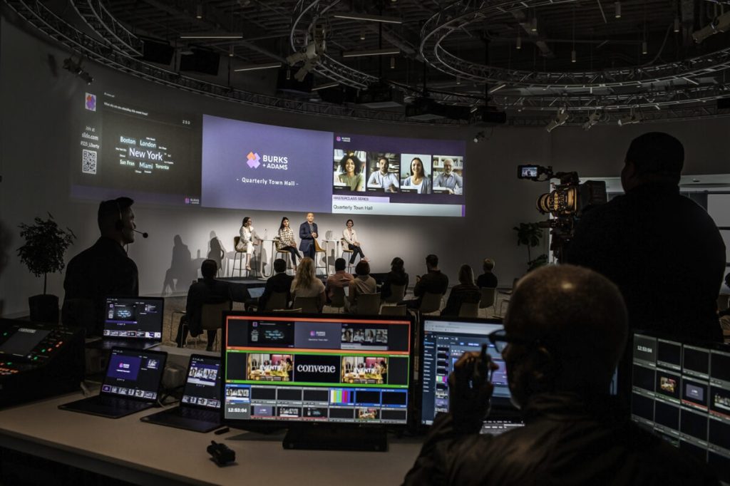 View of a conference taking place in a high-tech venue with projectors, cameras and sound equipment