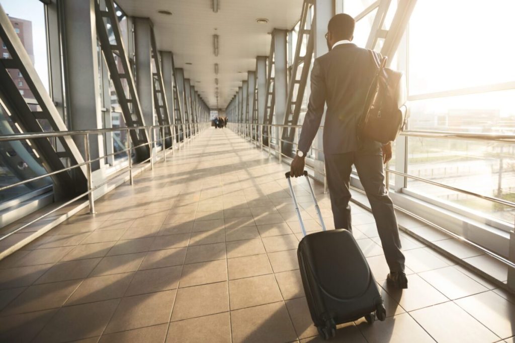 Back of a businessman with a suitcase in an airport.