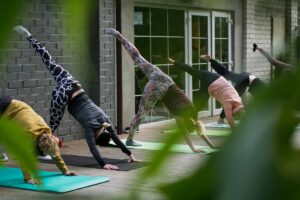 Wellness session with a group of women doing yoga on a deck outside a building