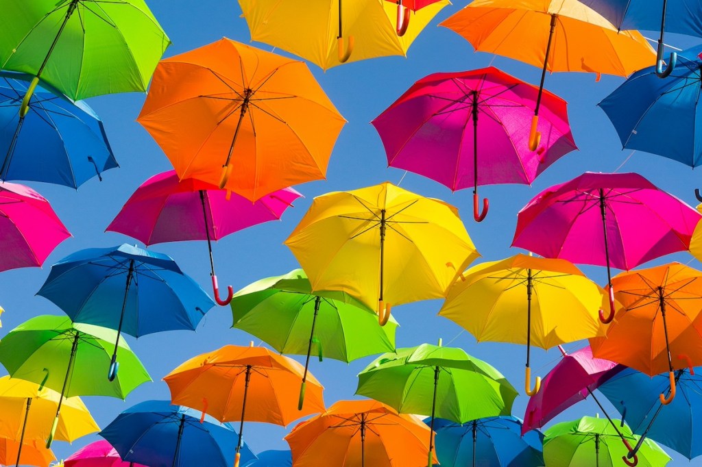 Multi colored umbrellas hanging overhead on a sunny day