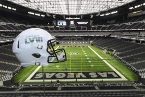 Super Bowl LVIII helmet held up with Allegiant Stadium in Las Vegas in the background