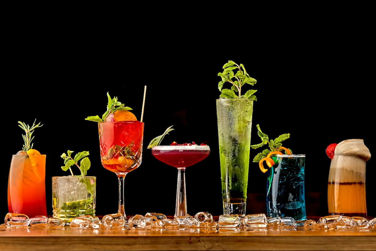 A wide variety of fancy-looking mocktails on a table topped with ice cubes