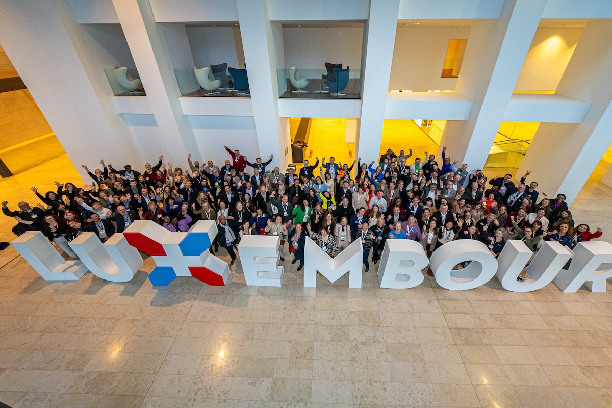 Meeting Professionals International European Meetings and Events Conference 2024 participants gathered around a Luxembourg sign at the European Convention Center Luxembourg