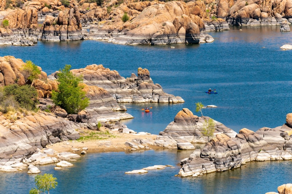 An overhead image of two kaykers on Watson Lake in Arizona. The lake enhances a sense of adventure with the otherworldly rock formations that surround it.