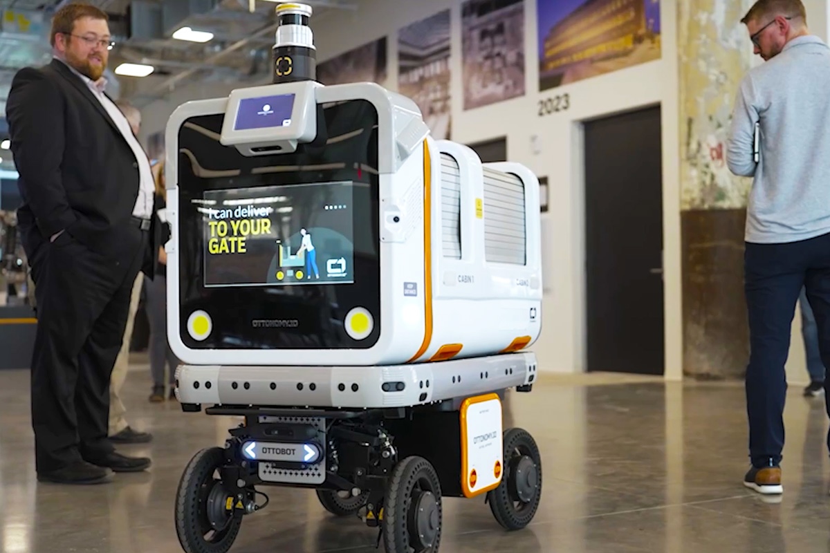 A robotic baggage carrier in Detroit's airport includes mechanized wheels and a camera for navigation purposes. The high-tech screen on the front of the robot reads, "I can deliver to your gate."