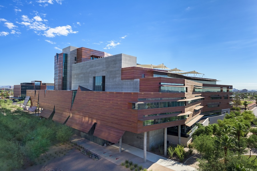 An aerial shot of the Phoenix Bioscience Core, an expansive multi-story center with an ultra-modern exterior combining copper-toned wood paneling, green-tinted windows, and grey cement blocks.