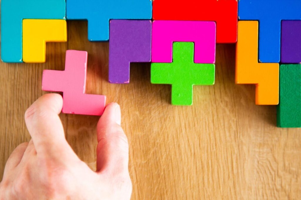 Hand arranging wooden puzzle pieces.