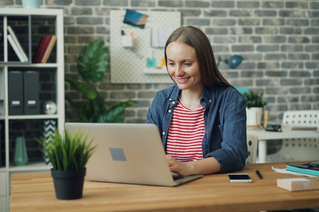 A woman sitting at a desk in a modern office using a laptop computer