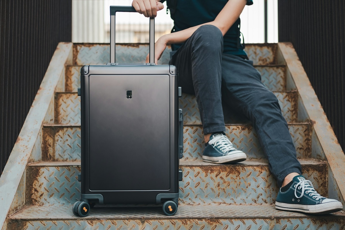 tting on a set of metal stairs with a suitcase