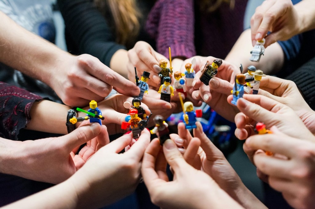 Group of people holding up lego figures in a circle