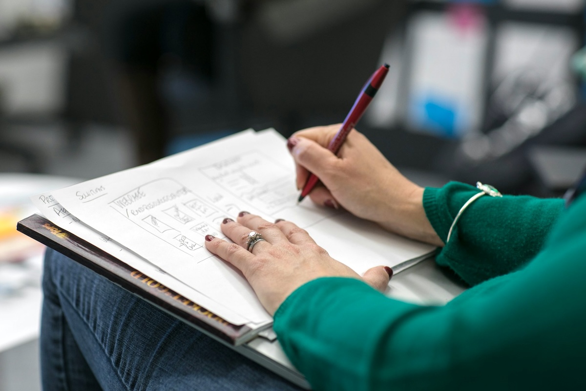 Person making notes on a paper pad on their lap