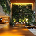 Lobby of a modern and upscale hotel with many plants, low lighting and comfortable seating