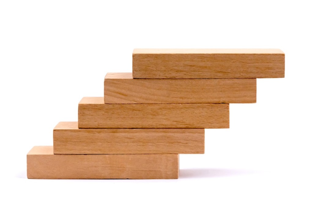 Small wooden blocks stacked as steps on a white background