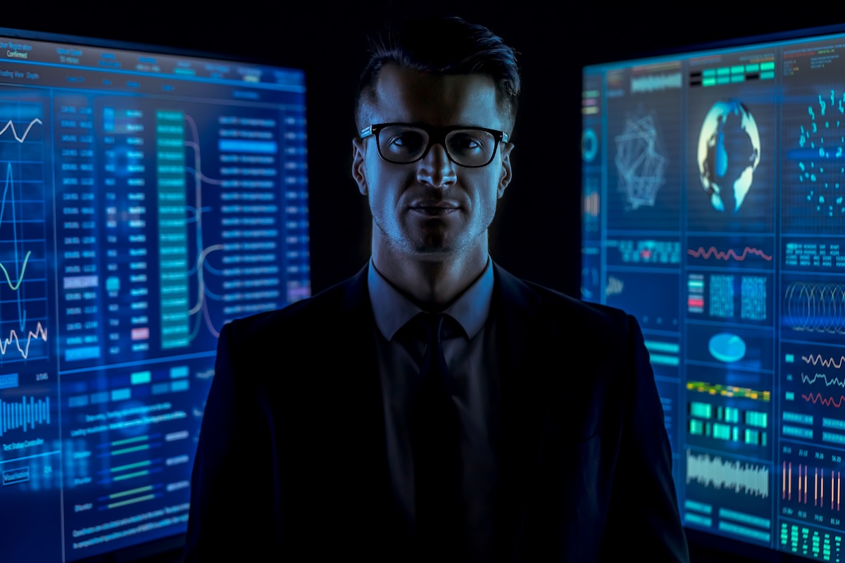 Man between computer monitors depicting deepfake scam